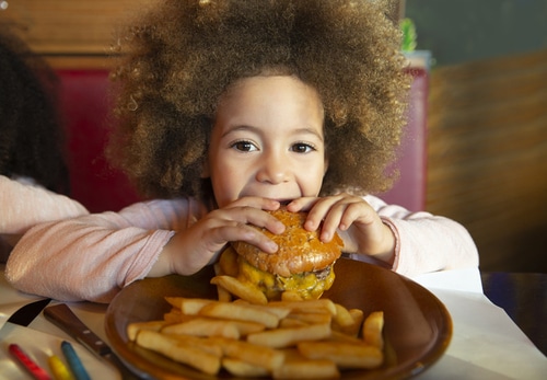 Niña comiendo una hamburguesa