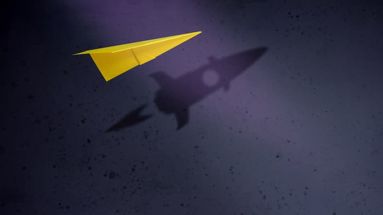 Avión de papel con un cohete en la sombra