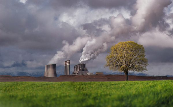 campo verde y fabrica echando humo gris
