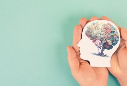 salud mental. manos sosteniendo una cabeza humana con un cerebro con flores