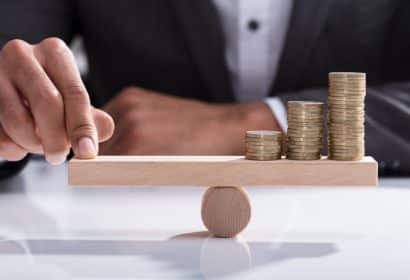 una mano sujetando en equilibrio tres montones de monedas