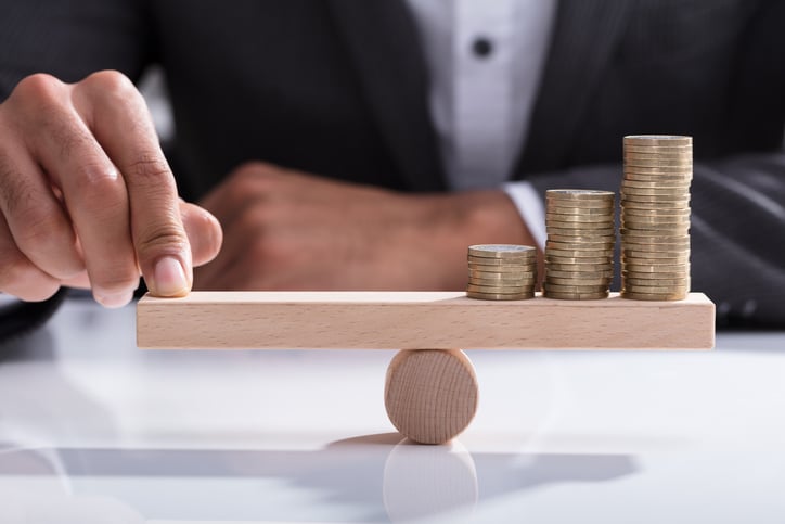 una mano sujetando en equilibrio tres montones de monedas