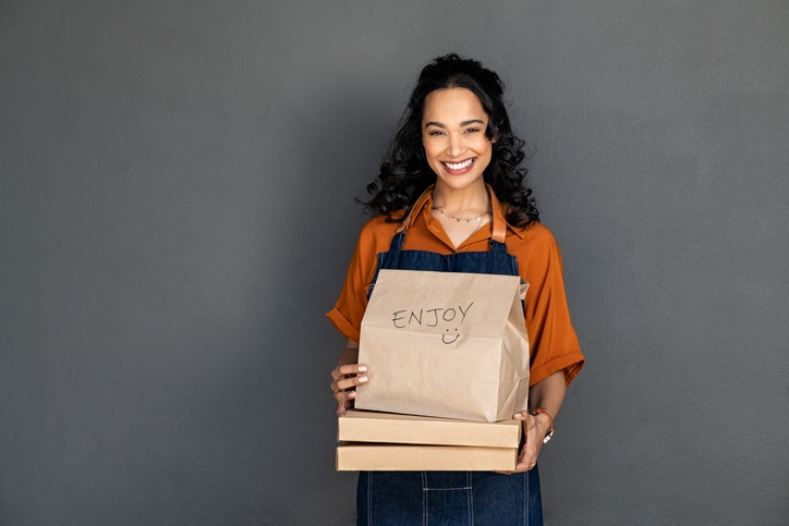 Mujer sonriente con un pedido de comida a domicilio