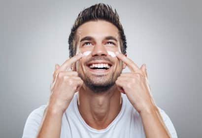 Hombre sonriente echándose crema hidratante