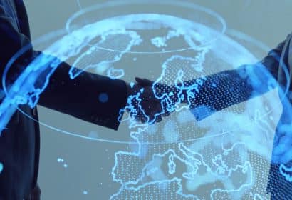 dos personas se dan la mano sobre un mapamundi